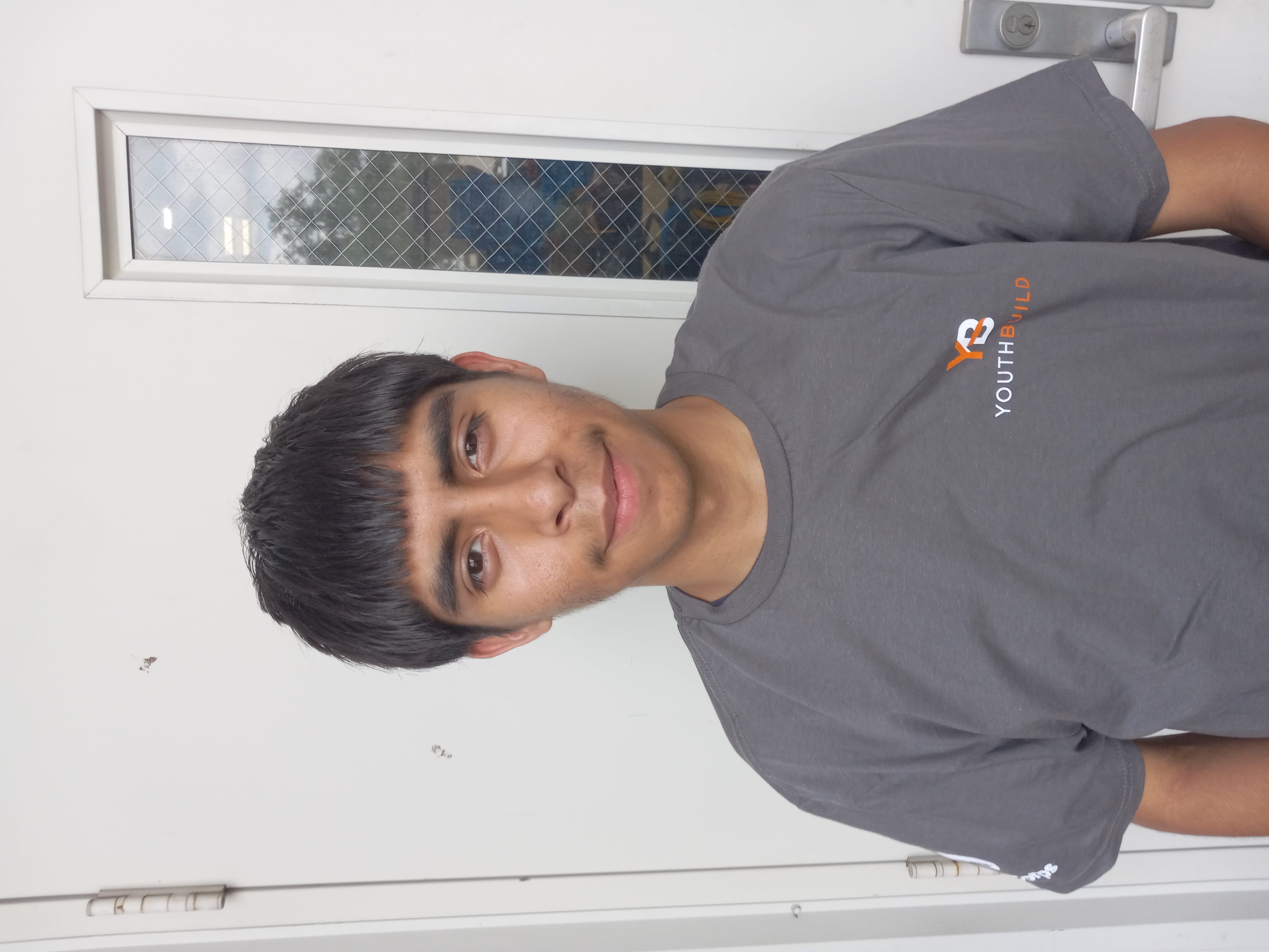Headshot of Robert Fabela wearing a gray youthbuild tshirt.